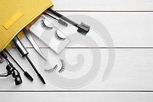 Flat lay composition with false eyelashes and tools on white wooden table. Space for text