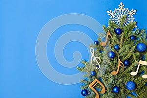 Flat lay composition with fir tree, Christmas decor and wooden music notes on color background.