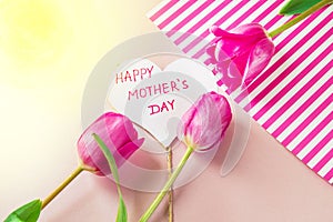 Flat lay composition with flowers and heart for mother's Day, greeting for women. Red tulips on pink background