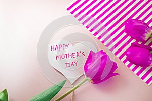 Flat lay composition with flowers and heart for mother's Day, greeting for women. Red tulips on pink background