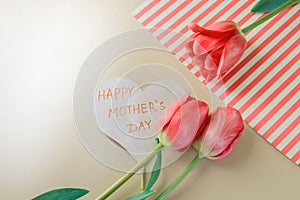 Flat lay composition with flowers and heart for mother's Day, greeting for women. Red tulips on pink background
