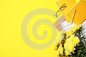 Flat lay composition with flowers and stationery on yellow background, space for text. Teacher`s day