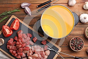Flat lay composition with fondue pot, raw meat, vegetables and spices