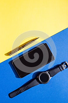 Flat lay composition for freelance blogger. Workspace with pen, stylish smartphone, black watch on colorful background