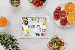Flat lay composition with fresh fruits and vegetables near tablet computer on wooden background