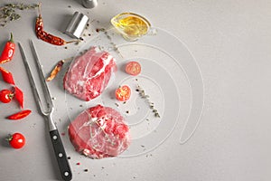 Flat lay composition with fresh raw meat, vegetables and spices on gray background
