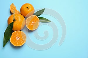 Flat lay composition with fresh ripe tangerines and leaves on blue background, space for text. Citrus fruit