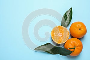 Flat lay composition with fresh ripe tangerines and leaves on blue background, space for text. Citrus fruit