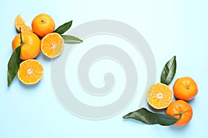 Flat lay composition with fresh ripe tangerines and leaves on light blue background, space for text. Citrus fruit