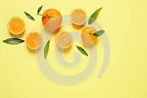 Flat lay composition with fresh ripe tangerines and leaves on yellow background, space for text. Citrus fruit