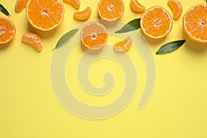 Flat lay composition with fresh ripe tangerines and leaves on yellow background, space for text. Citrus fruit