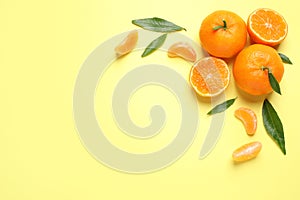 Flat lay composition with fresh ripe tangerines and leaves on yellow background, space for text. Citrus fruit