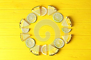 Flat lay composition with fresh sliced pineapple, lime and lemon on color wooden background