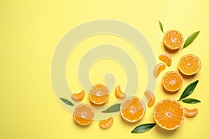 Flat lay composition with fresh tangerines and leaves on light yellow background, space for text. Citrus fruit