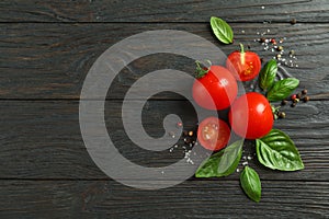 Flat lay composition with fresh tomatoes, salt, pepper and basil on wooden background, space for text