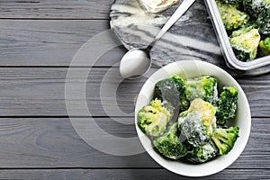 Flat lay composition with frozen broccoli on light grey wooden table, space for text. Vegetable preservation