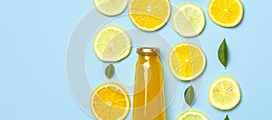 Flat lay composition with glass bottles of juice or fresh, slices of fresh lemon and orange, green leaves, ice cubes on blue