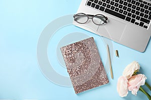 Flat lay composition with glittering notebook and laptop on color background