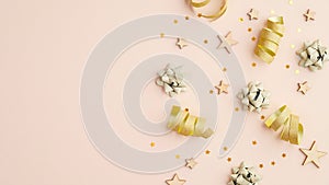 Flat lay composition with golden serpentine, party streamers, confetti stars on beige table. Top view with copy space. Invitation