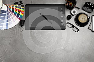 Flat lay composition with graphic drawing tablet and office items on grey stone background, space for text. Designer`s