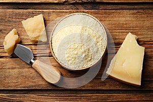 Flat lay composition with grated parmesan cheese and knife on wooden table