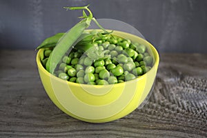 Flat lay composition with green peas in a green plate on wooden background.