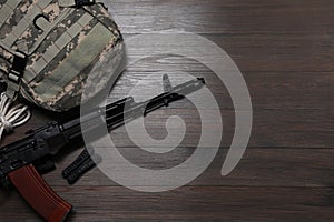 Flat lay composition with gun and military knapsack on wooden table. Space for text