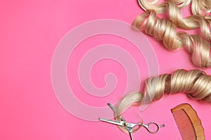 Flat lay composition with hair locks and tools on color background.