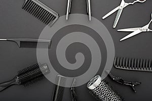 Flat lay composition with Hairdresser tools: scissors, combs, hair iron on black background with copy space for text in center.