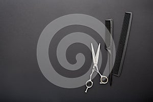 Flat lay composition with Hairdresser tools: scissors, combs, hair iron on black background with copy space for text. Frame.