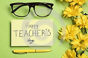 Flat lay composition with  HAPPY TEACHER`S DAY and flowers on light green background