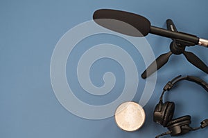 Flat lay composition with Headphones, microphone and coffee on a blue background. Podcast or webinar concept