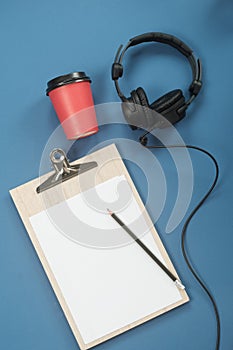 Flat lay composition with Headphones, microphone and coffee on a blue background. Podcast or webinar concept
