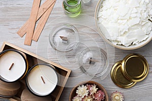 Flat lay composition with homemade candles and ingredients on light wooden background