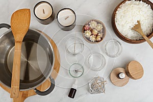 Flat lay composition with homemade candles and ingredients on white table
