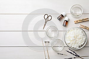 Flat lay composition with homemade candles ingredients on white wooden background. Space for text