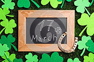 Flat lay composition with horseshoe and chalkboard on grass. St. Patrick`s Day