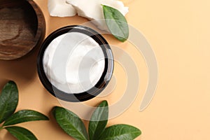 Flat lay composition with jar of coconut face cream on light orange background. Space for text