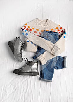 Flat lay composition with jeans, sweater and shoes on white
