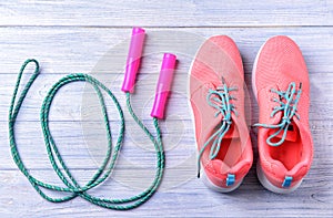 Flat lay composition with jumping rope and sneakers on wooden background. Gym workout