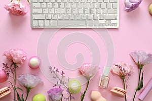 Flat lay composition with keyboard and flowers on pink background.
