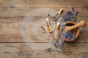 Flat lay composition with lavender flowers and natural essential oil on wooden table. Space for text