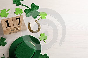 Flat lay composition with leprechaun hat and block calendar on white wooden table, space for text. St Patrick`s Day celebration