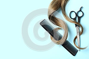 Flat lay composition with light brown hair, comb, scissors and space for text on color background.