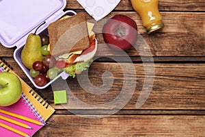 Flat lay composition with lunch box, tasty healthy food and school stationery on wooden table. Space for text