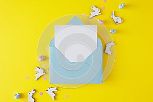 Flat lay composition made of blue open envelope with white card and cute easter bunnies