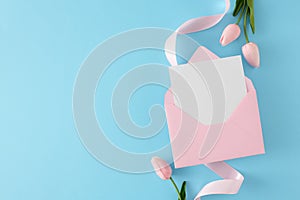 Flat lay composition made of envelope with letter, spring flowers and ribbon on blue background.