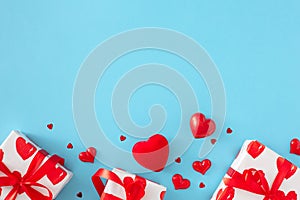 Flat lay composition made of gift boxes with silk ribbon and red hearts on pastel blue background
