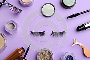 Flat lay composition with magnetic eyelashes and accessories on violet background