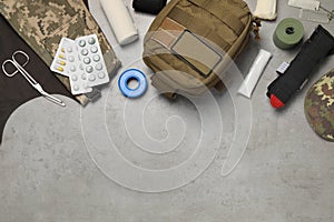 Flat lay composition with military first aid kit on light grey table. Space for text